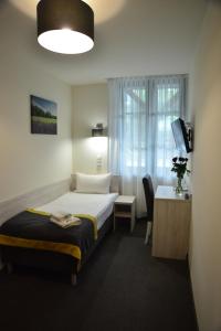 a hotel room with a bed and a desk and a window at Centrum Restauracyjno-Hotelowe Florres in Pawłowiczki