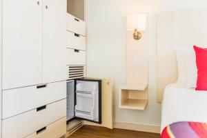a small bedroom with a bed and a small refrigerator at Hotel Londres Estoril / Cascais in Estoril