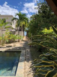 a swimming pool in front of a house with palm trees at Villa Sirandane in Baie du Tombeau