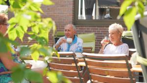 dos personas mayores sentadas en una mesa bebiendo café en dS Hotel Bad Bentheim, en Bad Bentheim