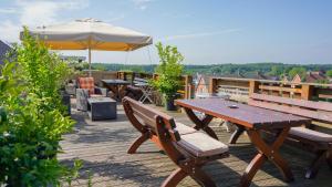a row of picnic tables and an umbrella on a deck at dS Hotel Bad Bentheim in Bad Bentheim
