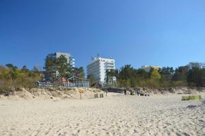 plaża z ludźmi chodzącymi po piasku i budynkach w obiekcie Apartament z panoramicznym widokiem na morze blisko plaży i centrum PL ENG DE w mieście Międzyzdroje