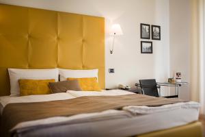 a bedroom with a large bed with a yellow headboard at Hotel Meridiana in Malcesine