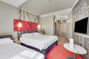 une chambre d'hôtel avec deux lits et une télévision à écran plat dans l'établissement ibis Saint Germain en Laye Centre, à Saint-Germain-en-Laye