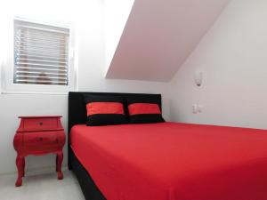 a bedroom with a red bed and a red nightstand at Villa Renata - Apartment Bijeli in Povlja