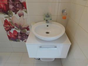 a white sink in a bathroom with a flower mural at Villa Renata - Apartment Bijeli in Povlja