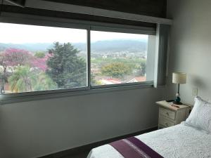 Schlafzimmer mit einem großen Fenster mit Aussicht in der Unterkunft Departamento - Edificio Los Naranjos in San Salvador de Jujuy + 1 Foto