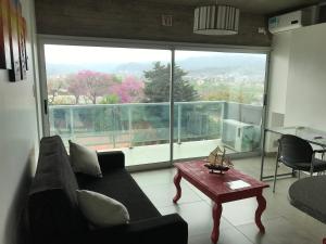ein Wohnzimmer mit einer Couch und einem Tisch und einem großen Fenster in der Unterkunft Departamento - Edificio Los Naranjos in San Salvador de Jujuy