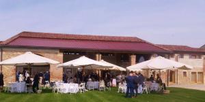 een groep tafels en witte parasols voor een gebouw bij Agriturismo Al Casale in Lonigo