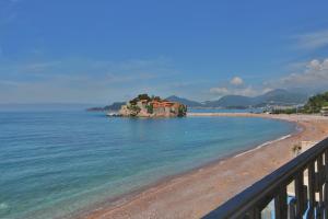 Montesan Beach Apartments Sveti Stefan في سفيتي ستيفان: شاطئ به منزل على صخرة في الماء