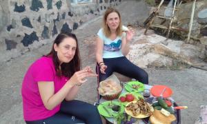 zwei Frauen sitzen an einem Tisch mit einem Teller Essen in der Unterkunft Shushan GUEST HOUSE in Yeghegnadzor