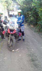 a man standing next to a motorcycle on a dirt road at Shushan GUEST HOUSE in Yeghegnadzor