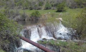 a river with waterfalls in the middle of a field at Shushan GUEST HOUSE in Yeghegnadzor