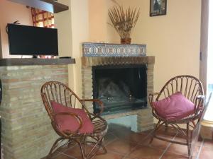 un soggiorno con 2 sedie e un camino di Alojamiento rural Esparteria a Cazorla