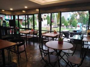梭桃邑的住宿－บ้านทิพรัตน์ สัตหีบ，餐厅设有桌椅和大窗户。