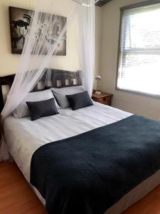 a bedroom with a large white bed with curtains at Loeriewood Garden Apartment, Hunters Home in Knysna