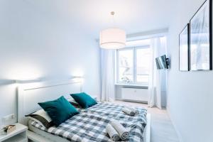 a white bedroom with a bed with blue pillows at Apartment Kuźnicza Wroclaw Old Town in Wrocław