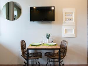 a dining room table with chairs and a television on the wall at Legend- Parking privé Gratuit- Terrasse privée- Wifi - Convert - Alimentec in Bourg-en-Bresse