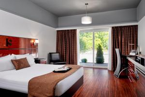 a hotel room with a bed and a desk and a window at Samuels Boutique Hotel in Goderich