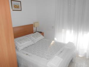 a white bed with white sheets and pillows in a bedroom at Hostal Ca La Irene in San Vicente de Castellet