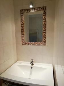 uma casa de banho com um lavatório branco e um espelho. em Le MAELY, studio au calme, centre de Honfleur (linge fourni) em Honfleur
