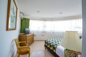 a bedroom with a bed and a desk and a window at Hotel Embajadores in Mérida