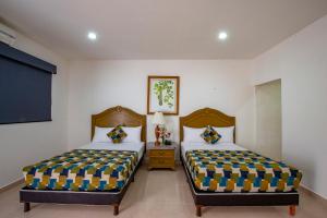 a bedroom with two beds and a flat screen tv at Hotel Embajadores in Mérida