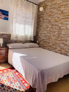 1 dormitorio con cama y pared de ladrillo en Residencial Lisboa, en Ceuta