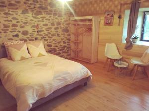 1 dormitorio con cama y pared de piedra en L étable au naturel, en Mauriac