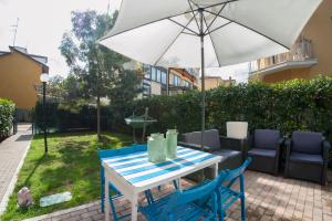 uma mesa com cadeiras azuis e um guarda-sol em Giardino di Annabella-giardino privato-posto auto em Bolonha