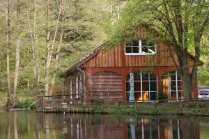 a small wooden cabin with a large window and a body of water at Hotel Boltenmühle in Gühlen Glienicke