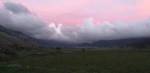 ein Feld mit wolkigem Himmel und Bergen im Hintergrund in der Unterkunft Chalet Vista Lago in San Gregorio