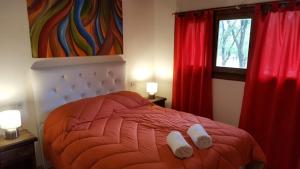 1 dormitorio con 1 cama con cortinas rojas y ventana en Magma Village en Los Reartes