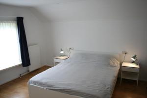 a white bed in a room with two night stands at vakantiewoning grensgebied Groningen/Drenthe/Friesland in Zevenhuizen