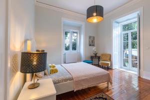 a white bedroom with a bed and a lamp at Graça Palace with Private Pool Garden in Lisbon