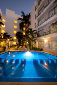 a swimming pool in front of a building at night at Ambiance Suites in Canc&uacute;n