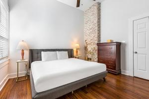 a bedroom with a white bed and a brick wall at Cozy and Charming House with Luxury Amenities in New Orleans