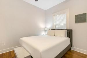 a white bedroom with a large bed and a window at Cozy and Charming House with Luxury Amenities in New Orleans +30 photos