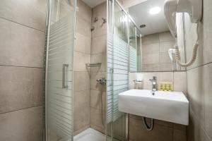 a bathroom with a shower, sink, and mirror at Argo Hotel Piraeus in Piraeus