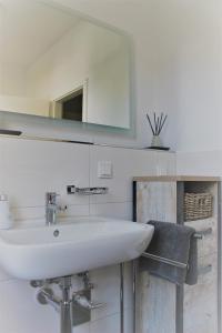 ein weißes Badezimmer mit einem Waschbecken und einem Spiegel in der Unterkunft Villa Köhler Ferienwohnung in Altenburg
