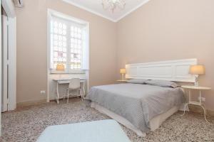 Biała sypialnia z dużym łóżkiem i biurkiem w obiekcie Le case d'un tempo w mieście Palermo
