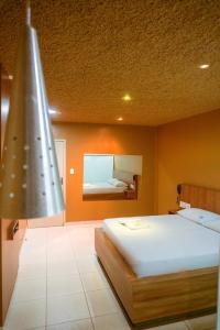 1 dormitorio con 1 cama grande y espejo en Jardins Motel (Adults Only), en Maceió