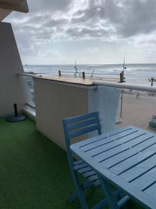 a blue table and chair on a balcony overlooking the beach at LACANAU FRONT DE MER in Lacanau