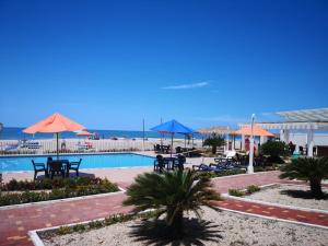 een zwembad met tafels en parasols en de oceaan bij Villa Altamar in Playas