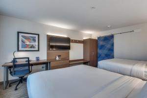 アディスンにあるHoliday Inn Express & Suites Dallas North - Addison, an IHG Hotelのベッド、デスク、コンピュータが備わるホテルルームです。