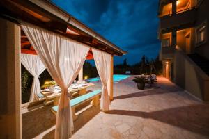 un patio al aire libre con cortinas y una piscina en Villa Kontrada, en Zadar