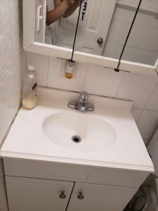 um lavatório branco na casa de banho com uma pessoa no espelho em Miami Cheapest Place em Miami