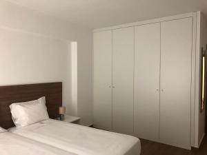 a bedroom with a bed and a large white cabinet at Marqueses de Ferreira in Lamas de Ferreira