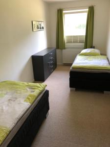 1 Schlafzimmer mit 2 Betten, einer Kommode und einem Fenster in der Unterkunft Modernes Apartment in ruhiger Lage, 70qm, 4 Personen in Brietlingen