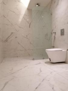 a white bathroom with a shower and a toilet at Vision Apartment in Buraydah